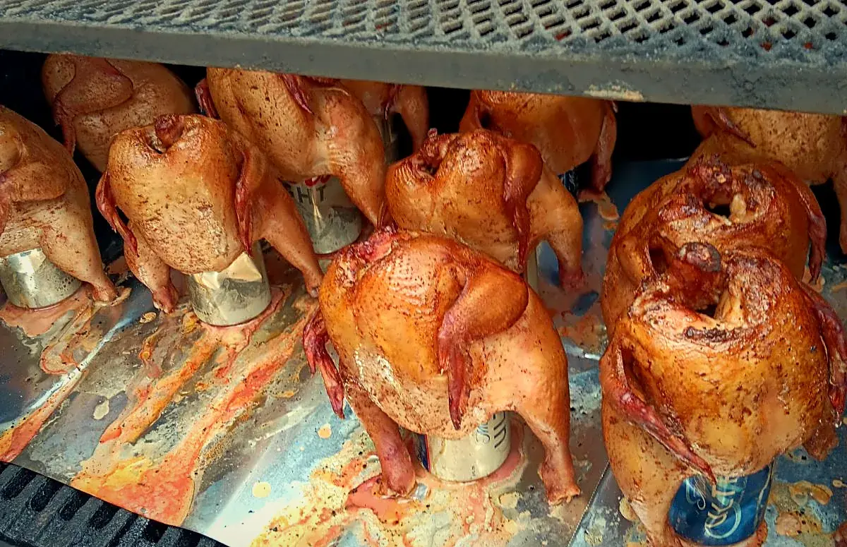 Rows of whole chickens standing upright in the smoker